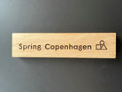 Logotype skylt med motiv "Spring Copenhagen". Material: Ek.